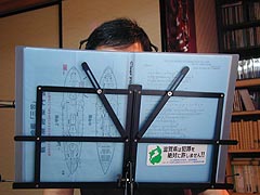 熱唱する森岡。尚、コードブックに貼られたステッカーは“滋賀県は犯罪を絶対許しません”、またブックの中には軍艦三笠の図面も(？)